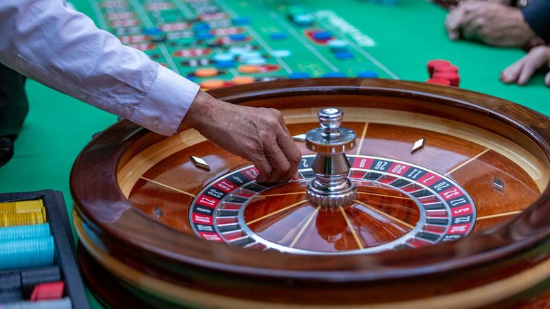 Hand van een croupier aan een houten roulettewiel, een klassieker onder casino spellen