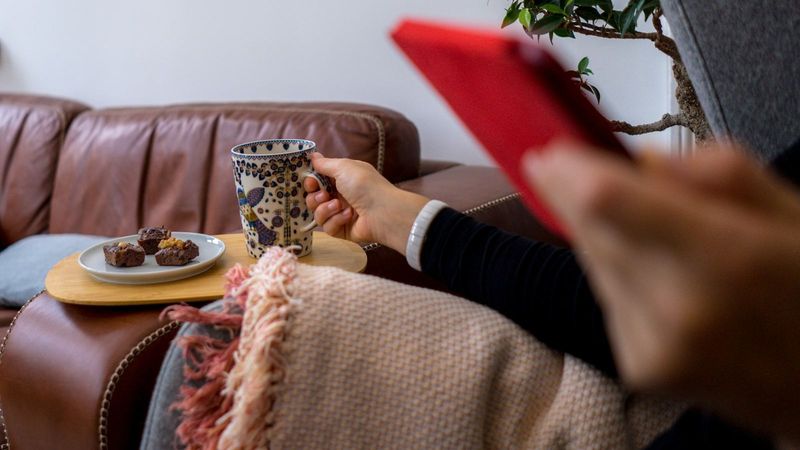 Ontspannen op de bank met koffie en telefoon, rustig nadenken over online gokken