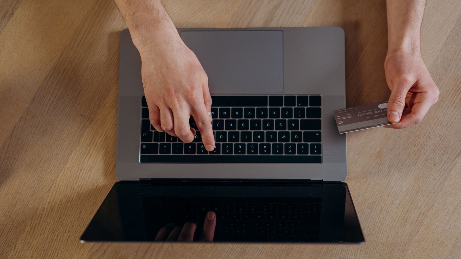 Handen met creditcard en laptop van bovenaf, betalen bij een creditcard casino
