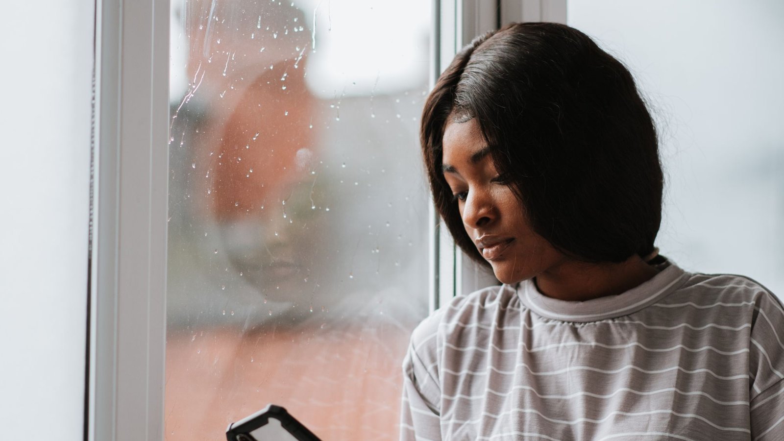 Vrouw bij het raam bekijkt rustig haar telefoon om zich in cruks te registreren