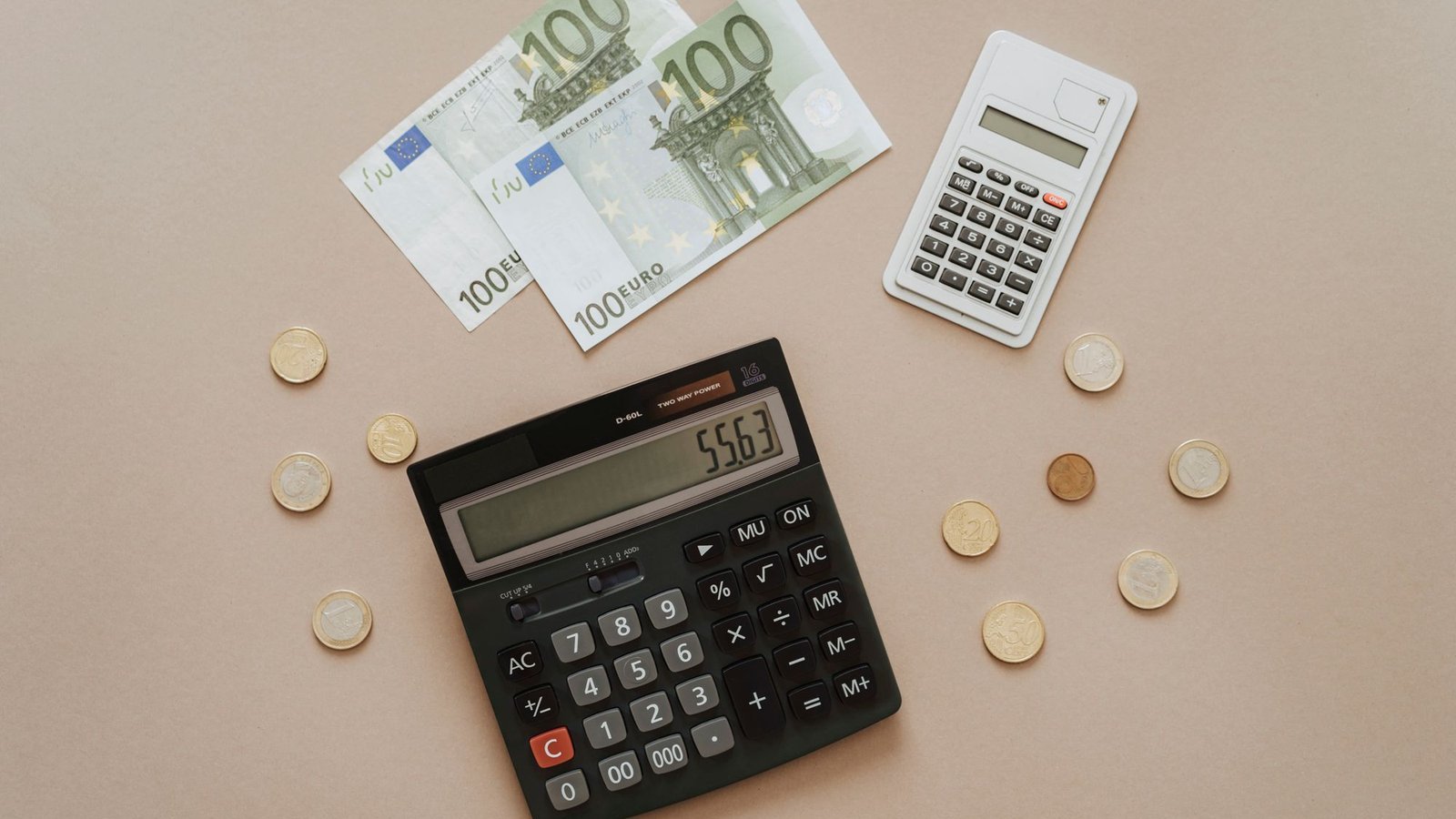 Rekenmachines, eurobiljetten en munten op tafel voor het berekenen van kansspelbelasting