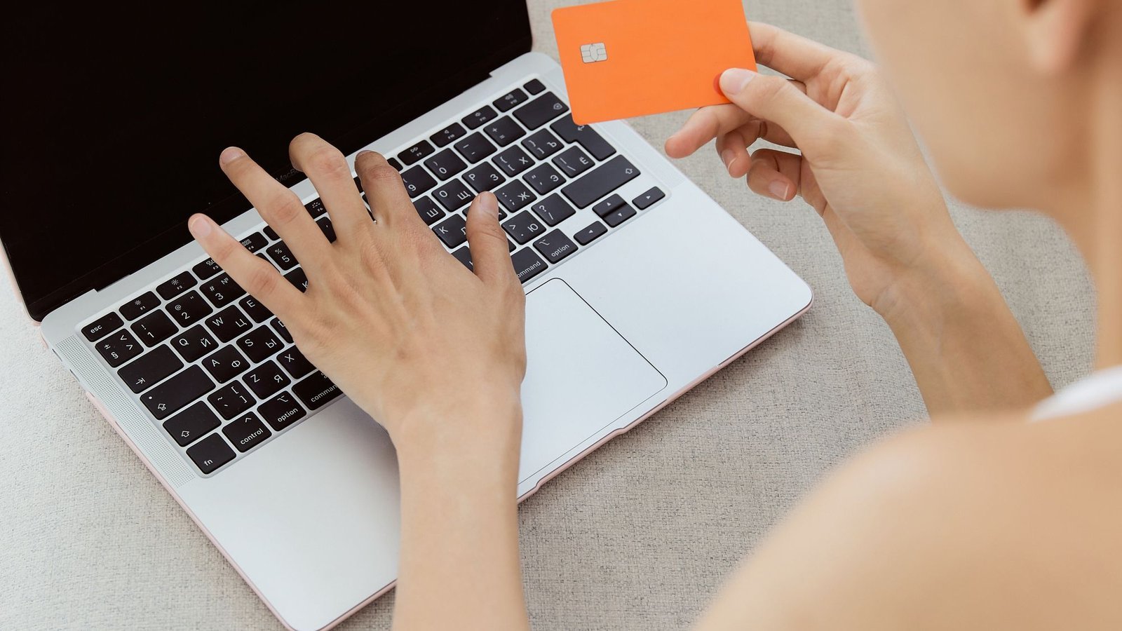 Vrouw met bankpas achter haar laptop vergelijkt verschillende online casino betaalmethoden