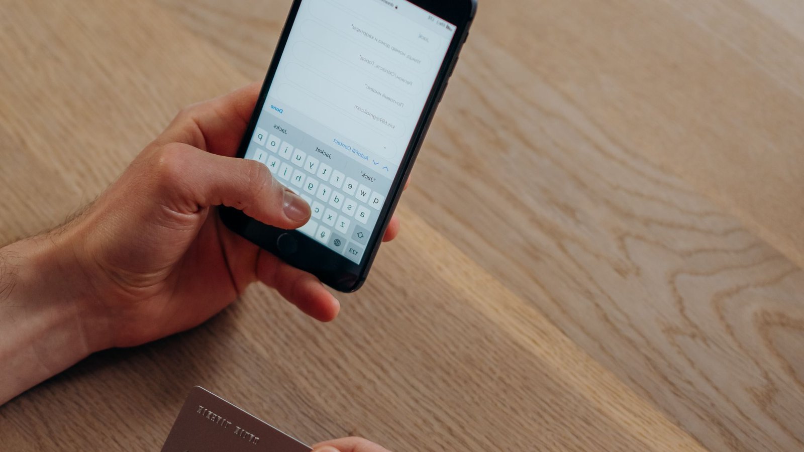 Persoon met smartphone en bankpas rondt een betaling af bij online casino iDEAL