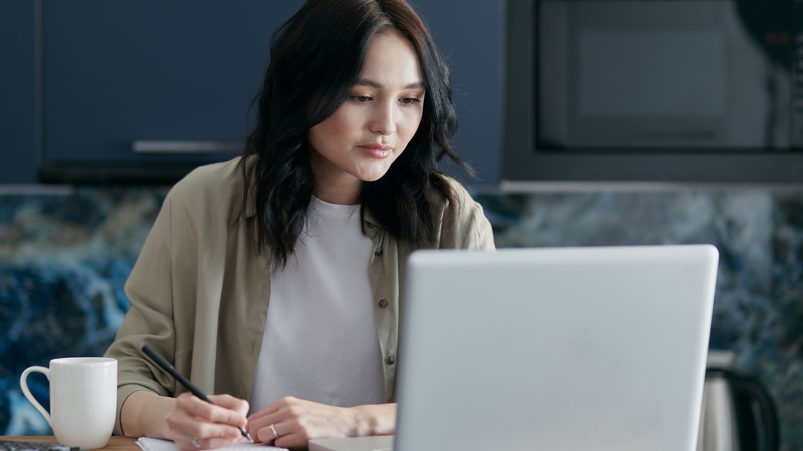 Vrouw met laptop en notitieblok gaat online casino vergelijken op vijf punten