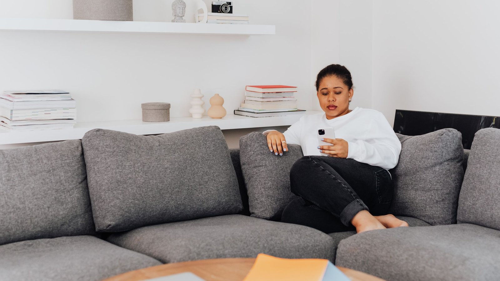 Uitbetaling weekend: vrouw op de bank kijkt op zaterdag op haar telefoon
